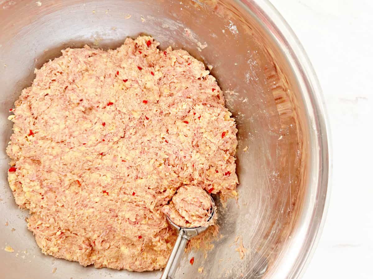 Down view of mixing bowl with sausage balls mixture and cookie scoop.