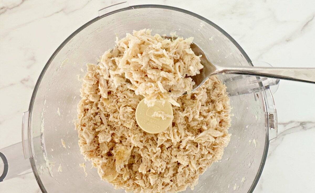 Down view of shredded chicken breasts in food processor.