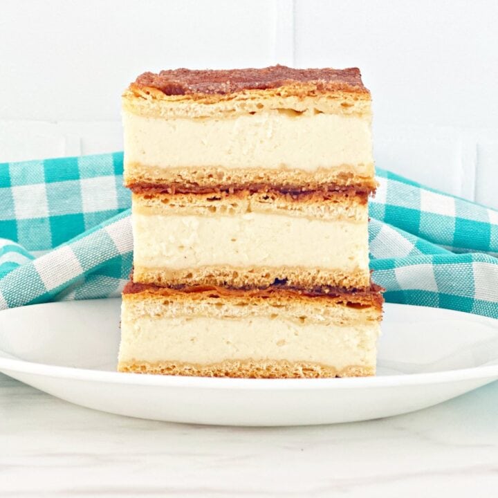 Three sopapilla cheesecake with condensed milk stacked on white plate.