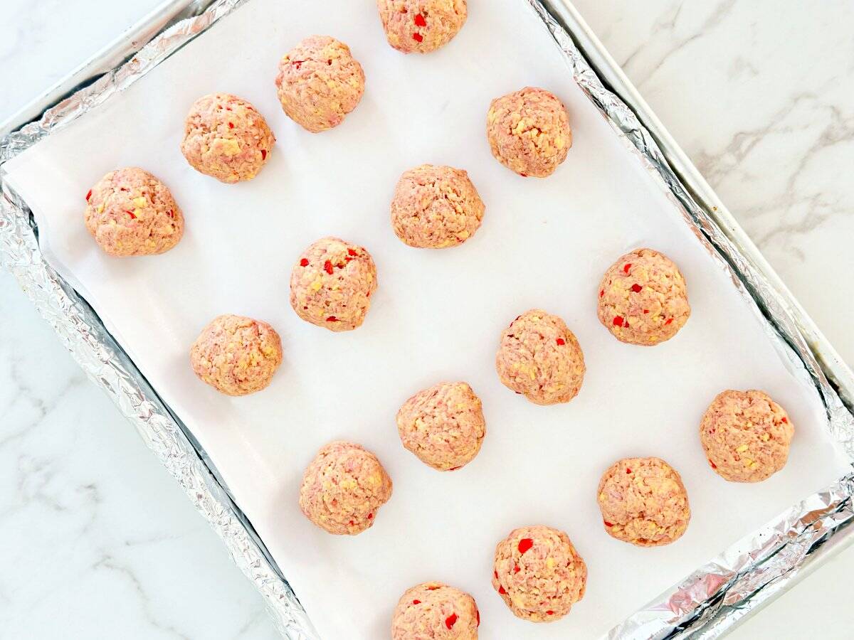 Down view of unbaked pimento cheese balls on sheet pan.