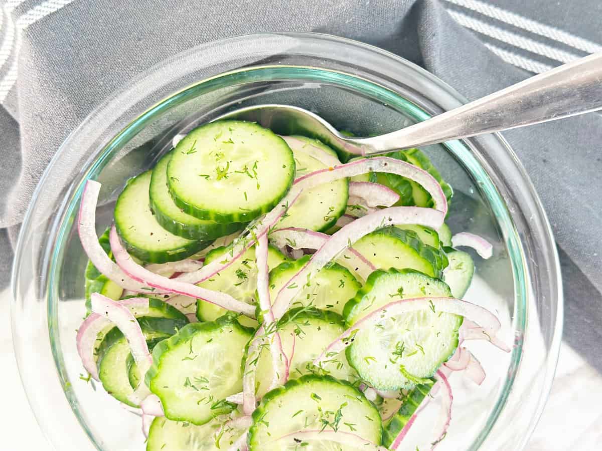 Down view of clear mixing bowl with vinegar cucumber salad.