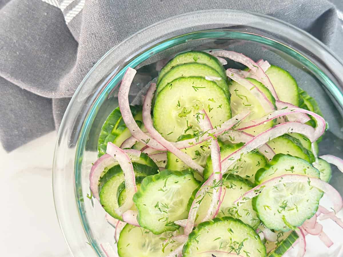 Down view of clear mixing bowl with vinegar cucumber salad.