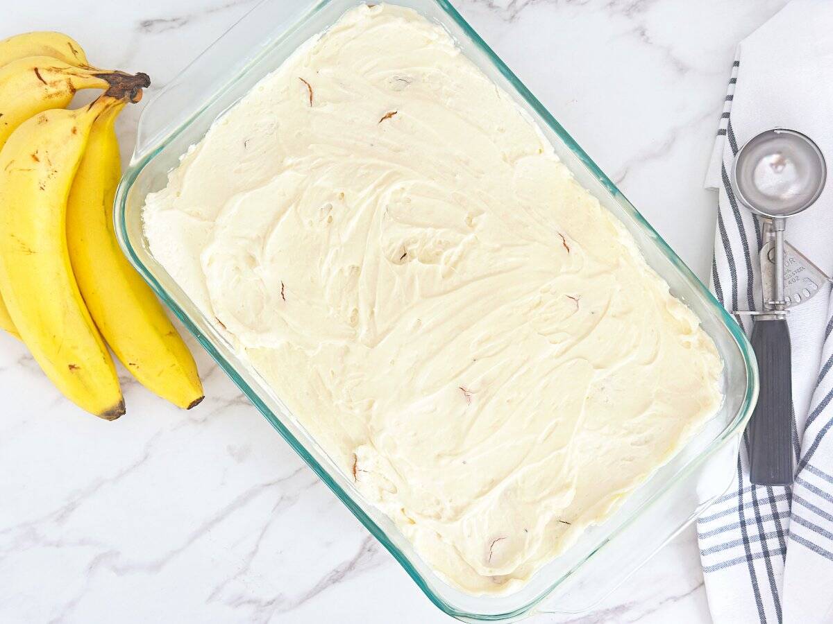 Down view of copycat magnolia bakery banan pudding. Next to a silver ice cream scoop and fresh bananas.