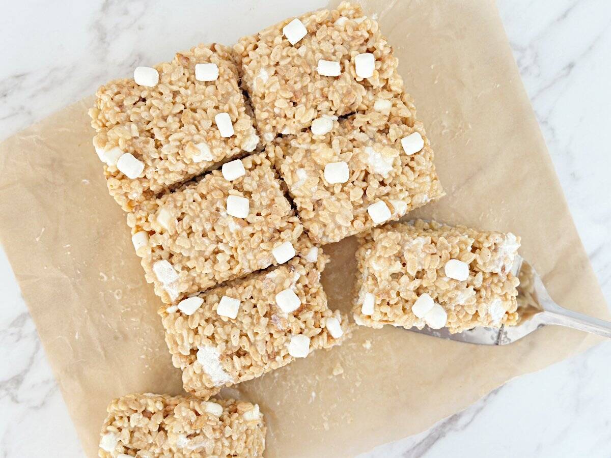 Down view of cut condensed milk rice krispies treat on brown parchment paper.