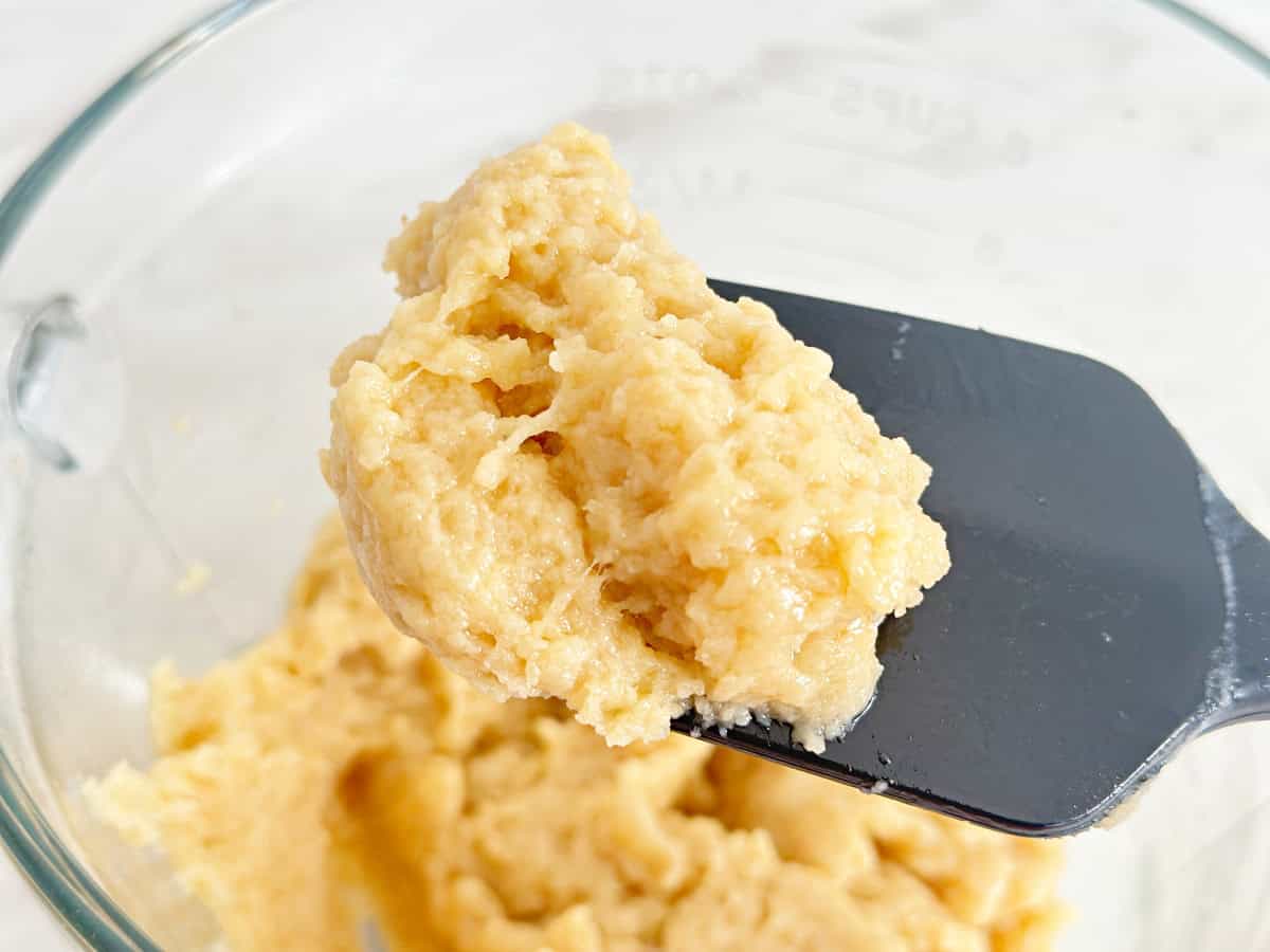 Side view of drop biscuit mixture on black rubber spatula.