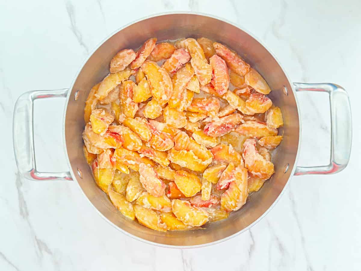 Down view of a pot with sliced frozen peaches.