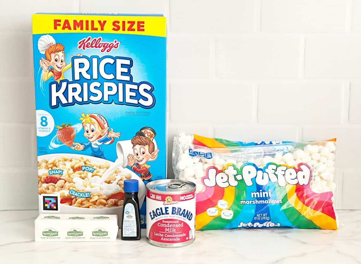 A box of rice krispies cereal, canned condensed milk, butter, vanilla extract, and a bag of marshmallows.