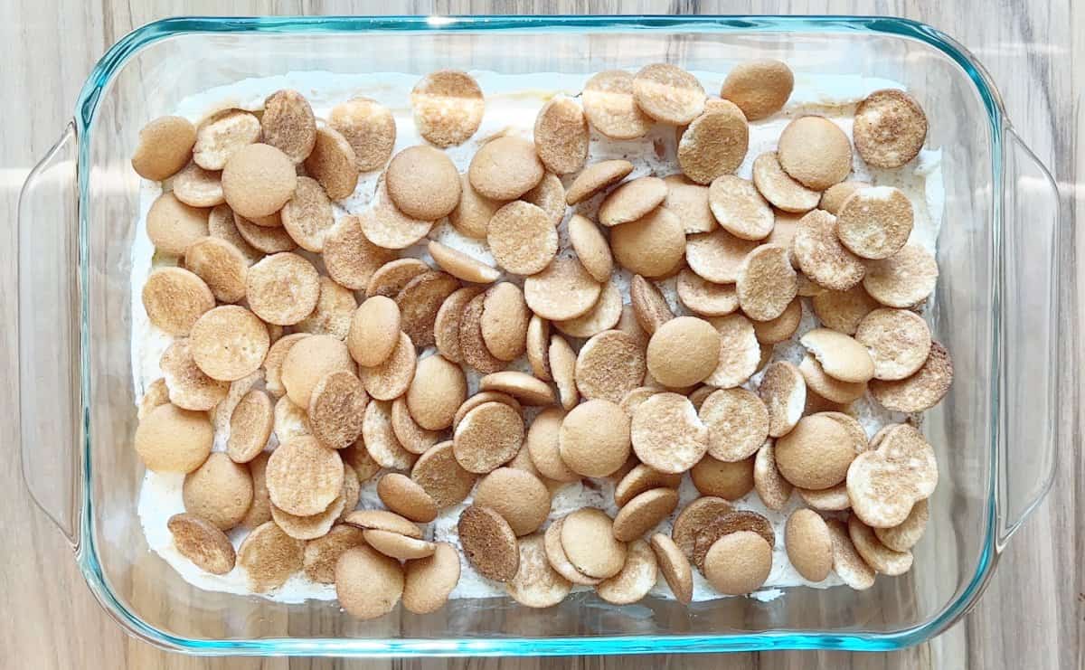 Down view of a glass 9x13 baking dish with a layer of banana pudding mixture and mini nilla wafers.