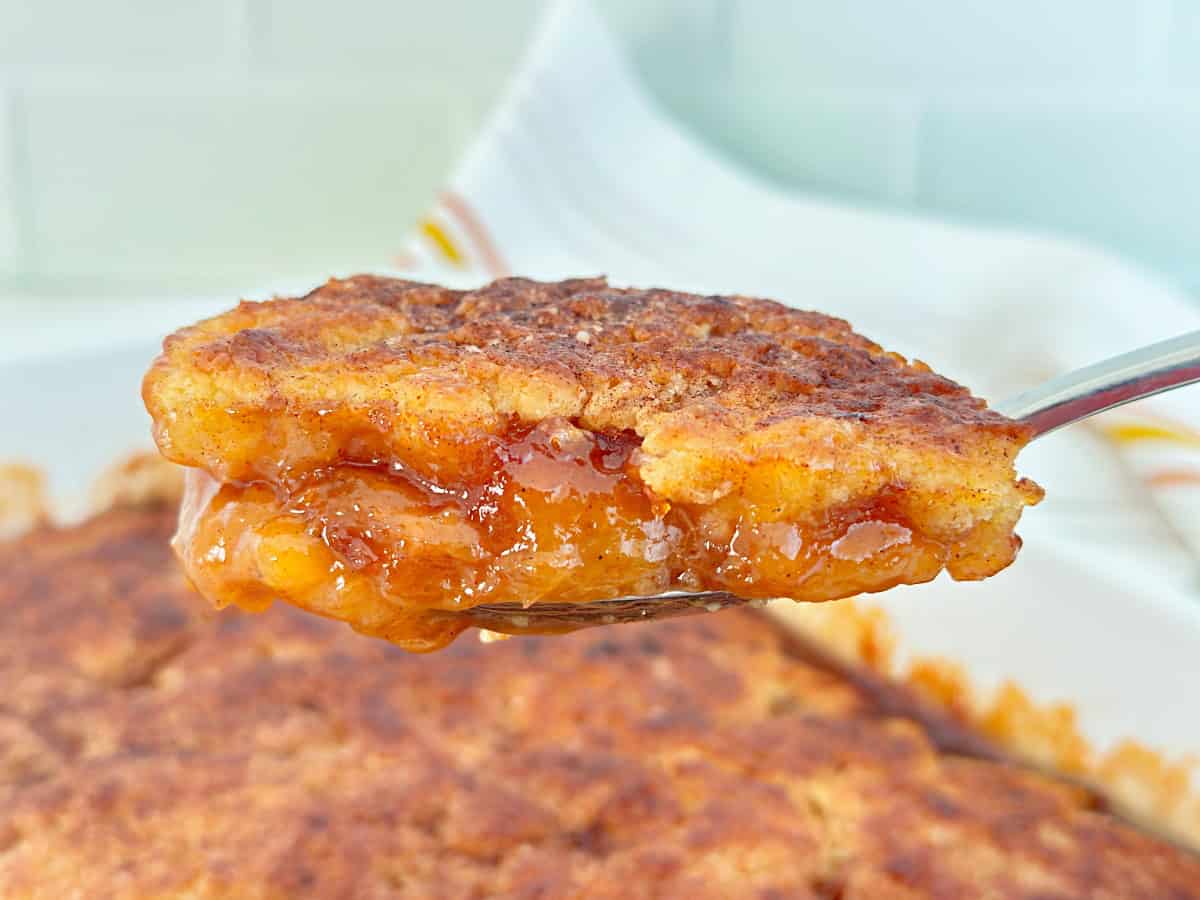 Old fashioned peach cobbler on silver serving spoon.