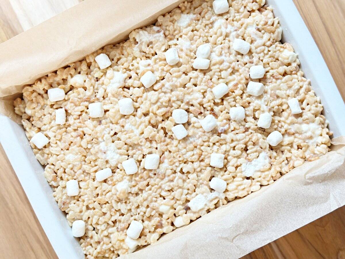 Down view of uncut rice krispies treats in parchment lined baking pan.