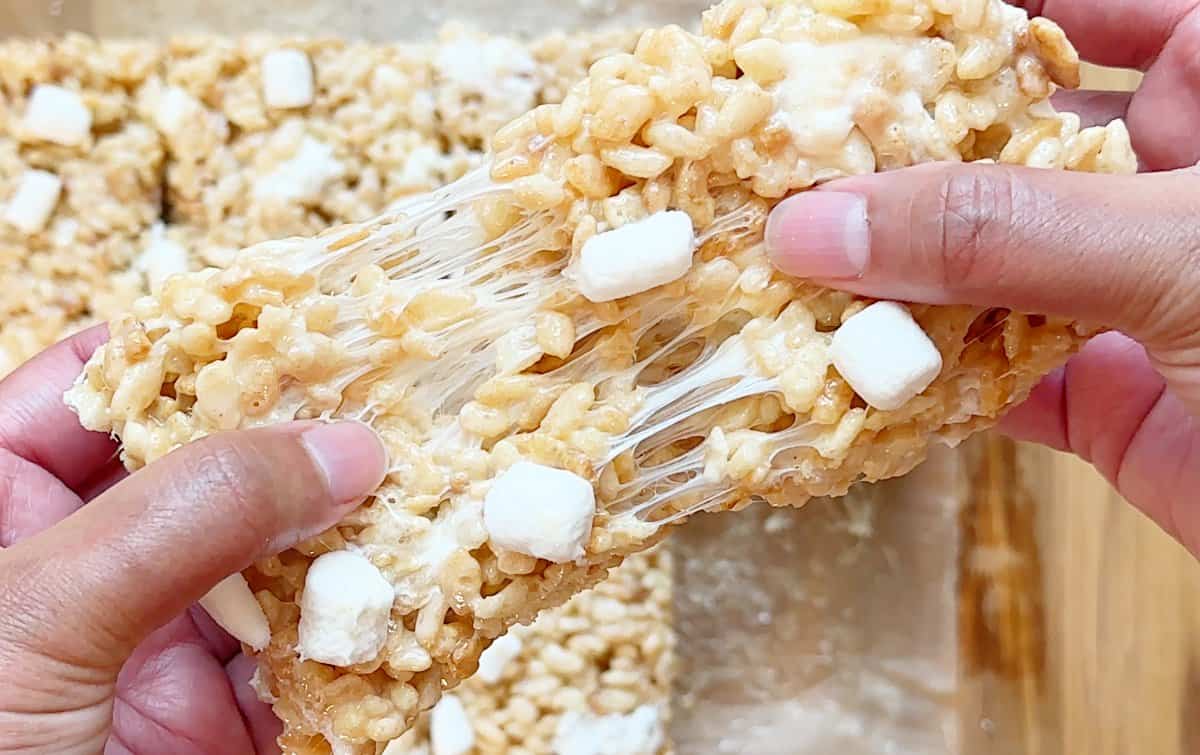 Hands pulling a piece of condensed milk Rice Krispies treats. Stretchy marshmallow texture.