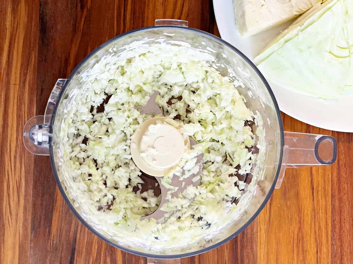 Down view of food processor jar with chopped cabbage.