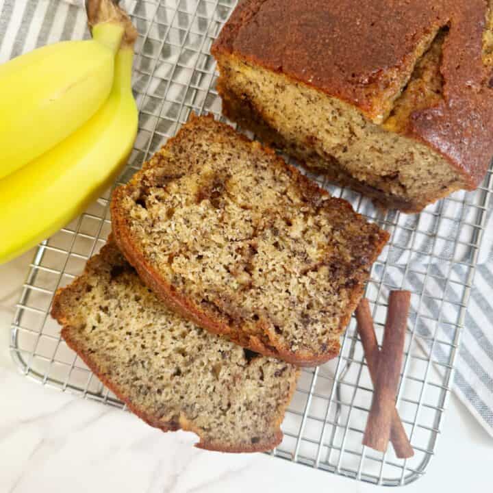 Cinnamon banana bread with oil on silver cooling rack. Slices and a whole loaf.