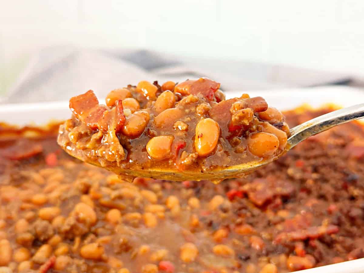 Spoonful of cowboy baked beans with canned bush's baked beans, sweet baby ray's bbq sauce, bacon, and ground beef.