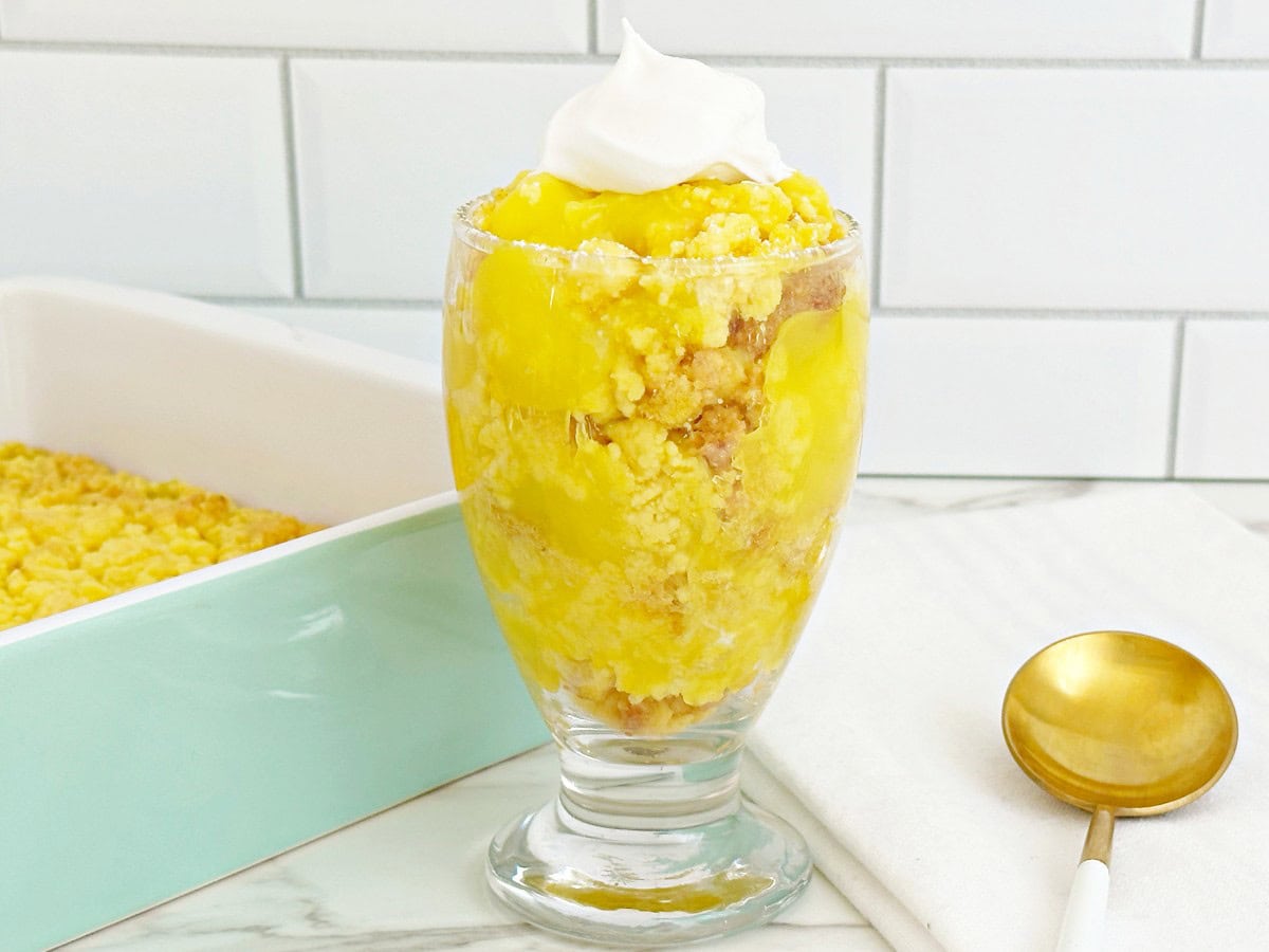 Lemon crumble dessert in a glass cup topped with whipped cream.