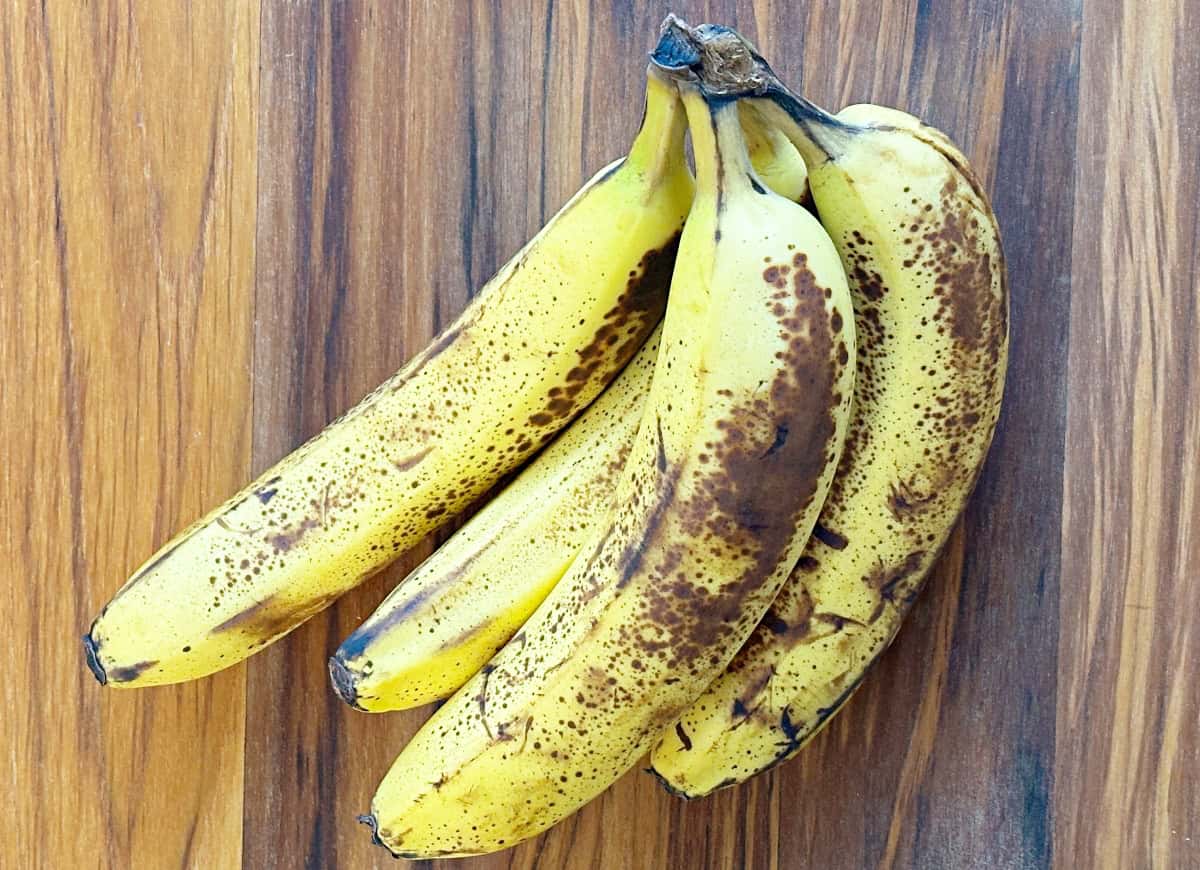 Bunch of ripe bananas that have brown speckles.