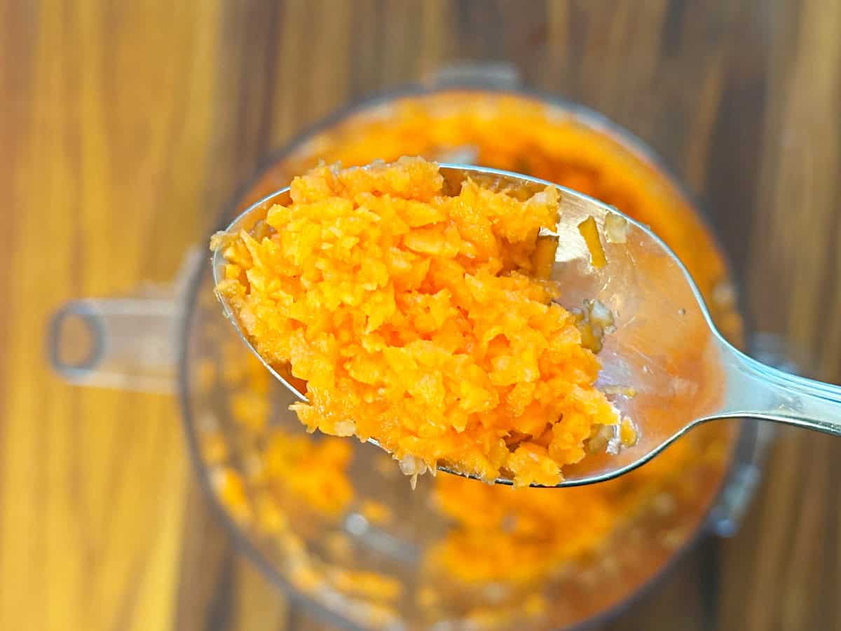 Down view of silver spoon with shredded carrots.