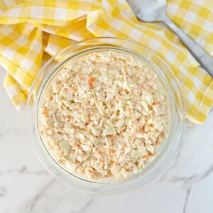 A bowl of southern coleslaw with mayonnaise next to a spoon.