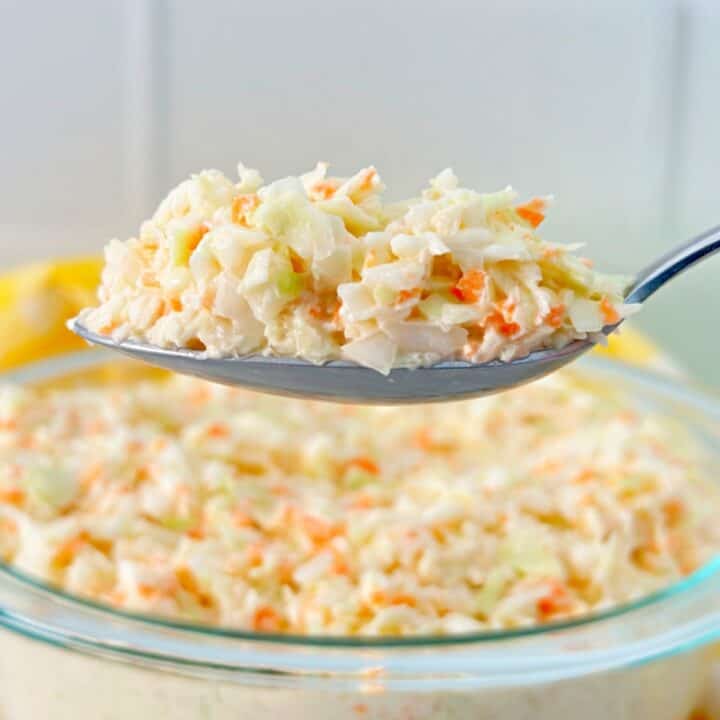 Southern coleslaw with mayonnaise on silver serving spoon.
