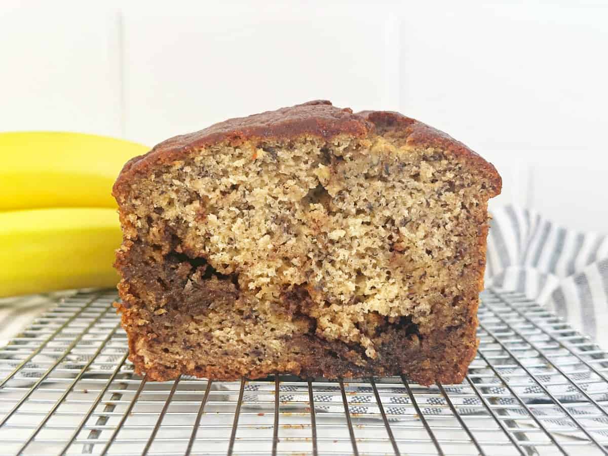 Side view of cut cinnamon banana bread on cooling rack.