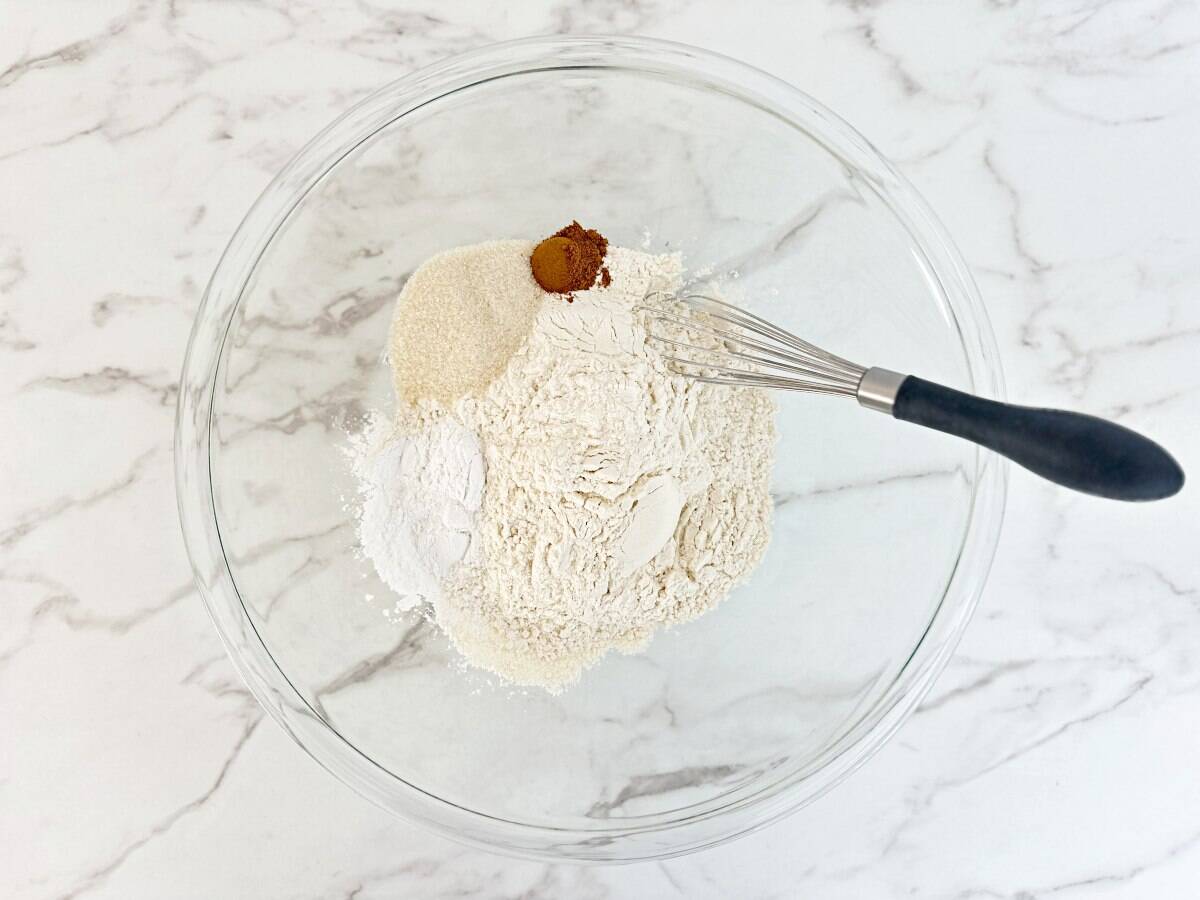 Clear mixing bowl with prepped dry ingredients and a whisk.