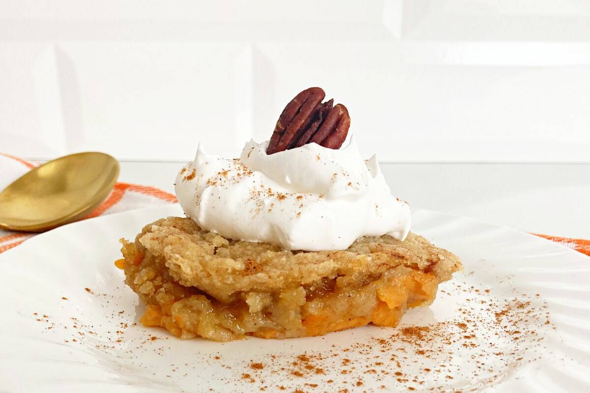 White plate with cake mix sweet potato cobbler, next to gold spoon and white orange napkin.