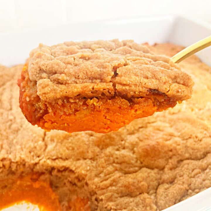 Pumpkin cobbler with cake mix on a gold serving spoon.