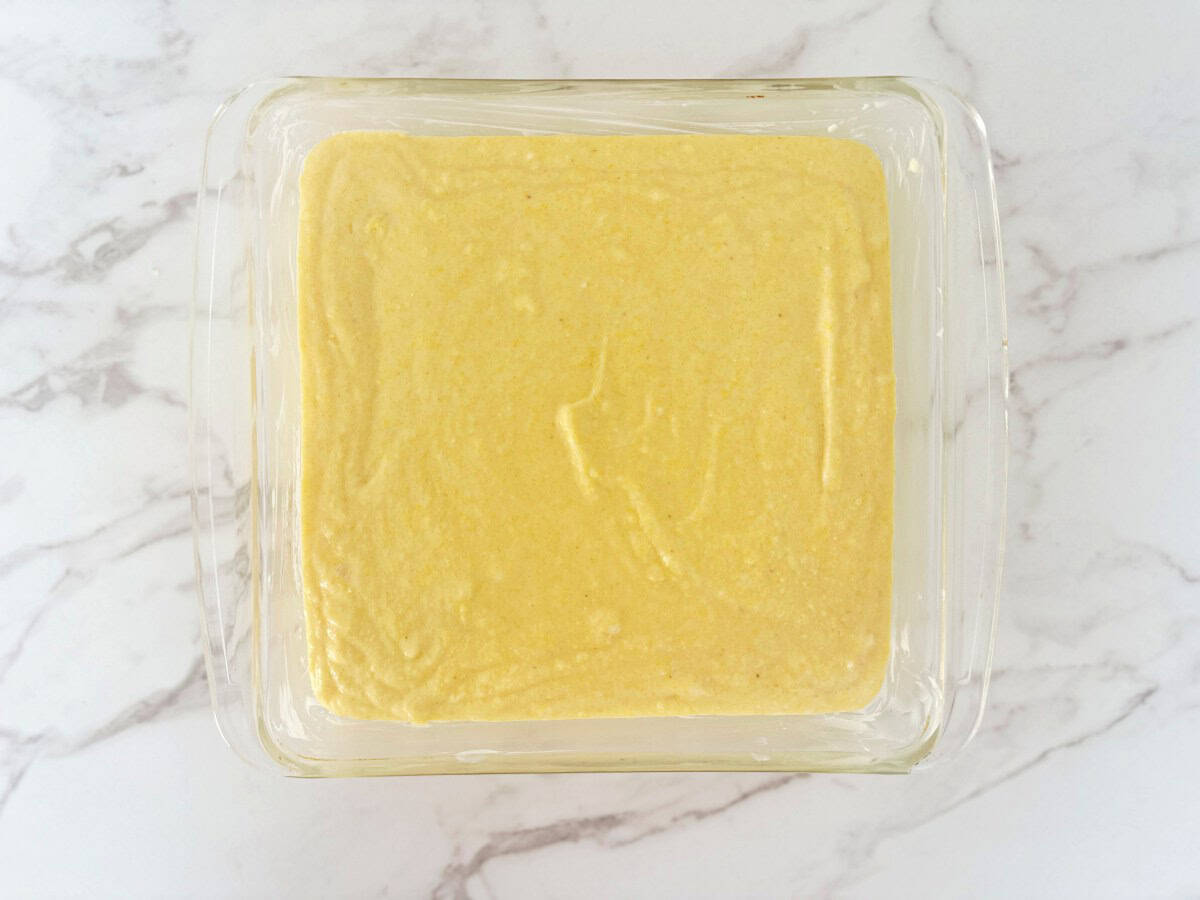 Unbaked cornbread in a glass baking dish, down view.